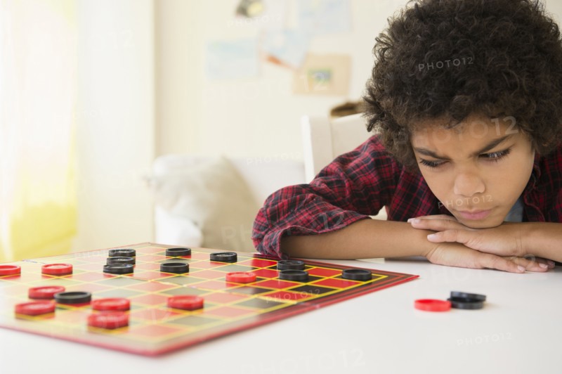 Angry mixed race boy losing game of checkers