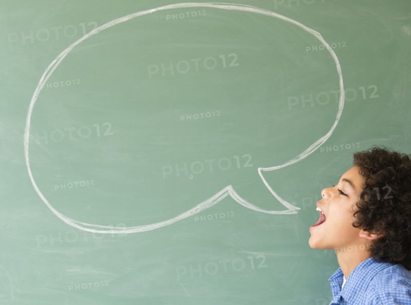 Mixed race boy shouting into speech bubble on chalkboard
