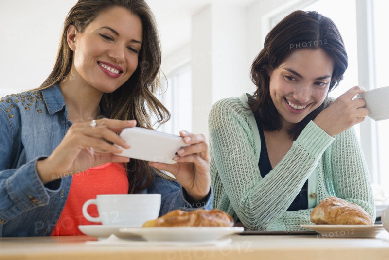 Hispanic women taking cell phone photograph of breakfast