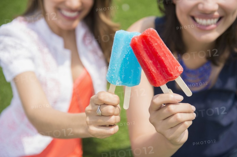Hispanic women eating popsicles outdoors