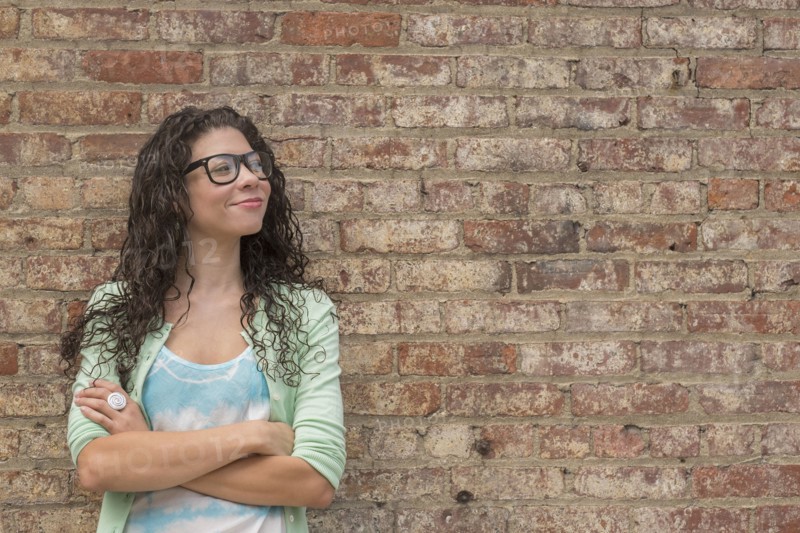 Pensive mixed race woman standing with arms crossed