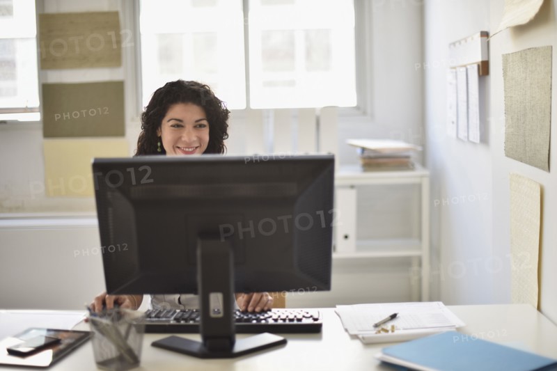 Mixed race businesswoman working on computer at desk in office