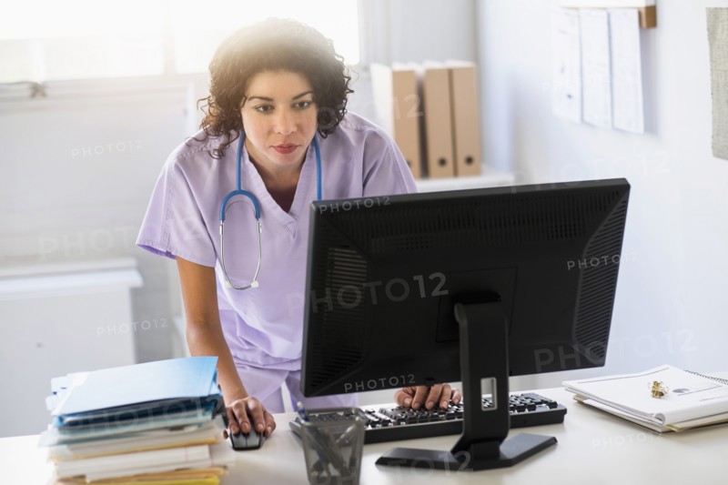 Mixed race nurse using computer in office