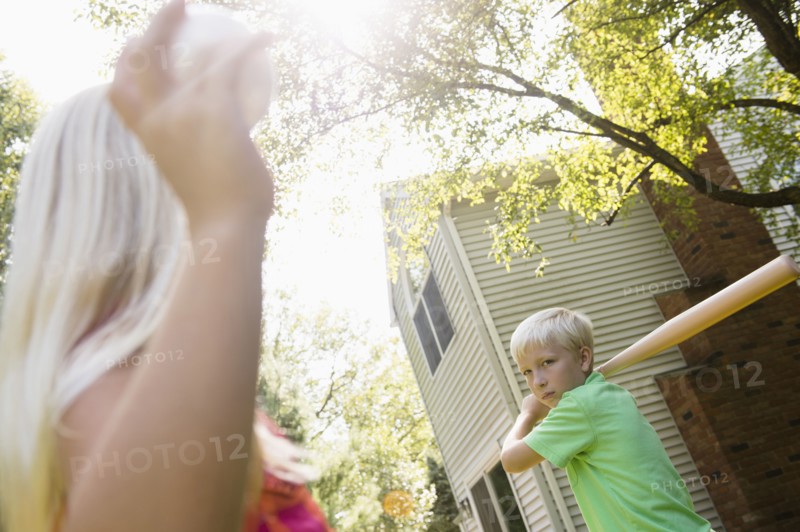 Caucasian children playing baseball in backyard