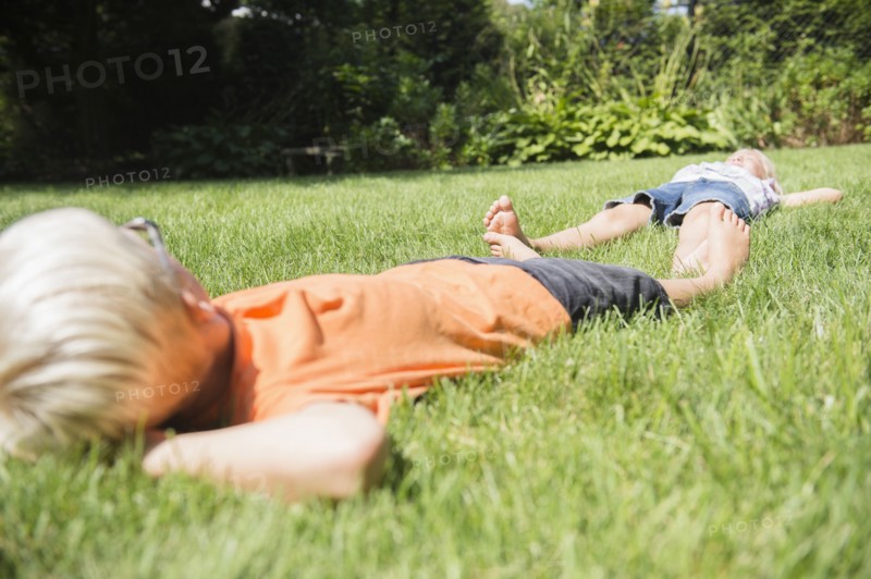 Caucasian children laying on lawn in backyard