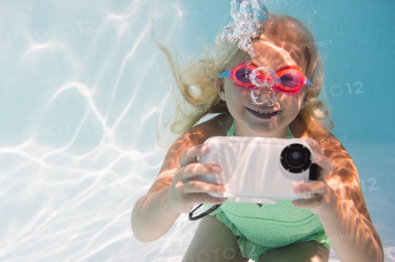 Caucasian girl taking photograph underwater in pool