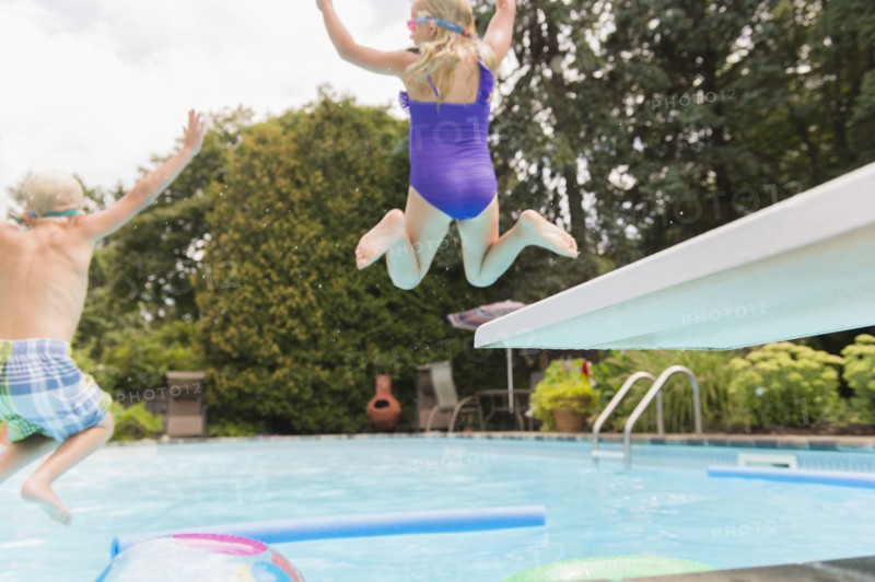 Caucasian children jumping into swimming pool