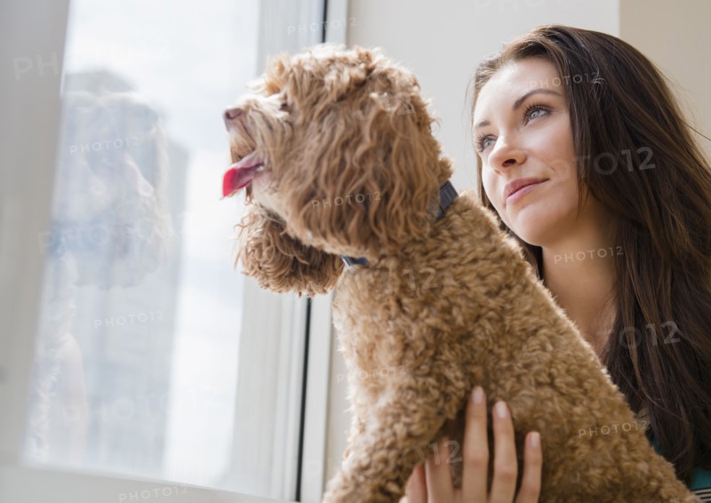 Caucasian woman looking out window with pet dog