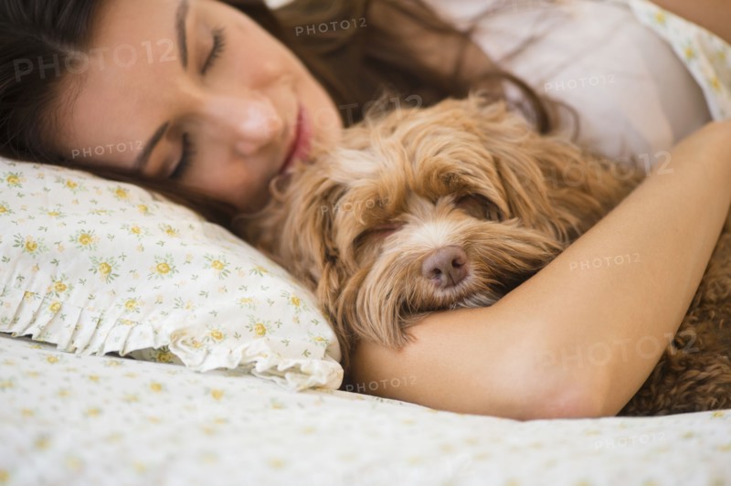 Caucasian woman hugging pet dog in bed