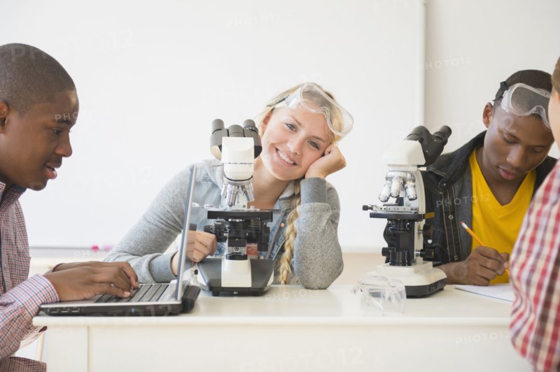 Teenage students using microscopes in science laboratory