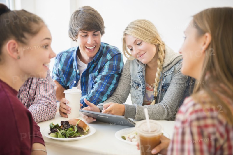 Teenagers using digital tablet at table