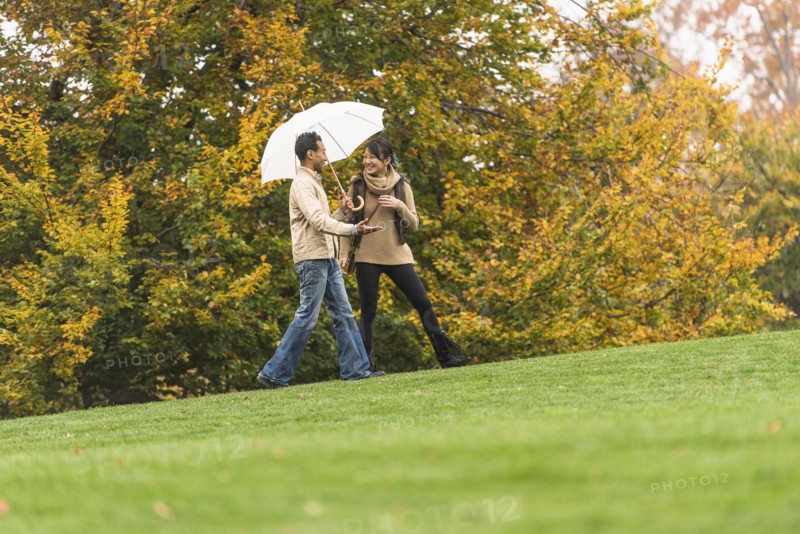 Couple walking with umbrella in park