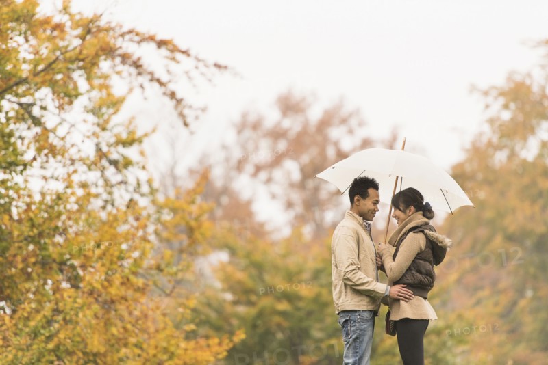 Couple standing with umbrella in park