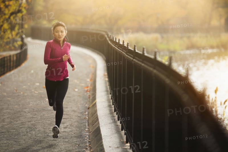 Asian woman running on waterfront path