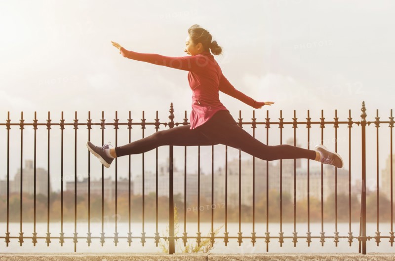 Asian woman leaping on waterfront path