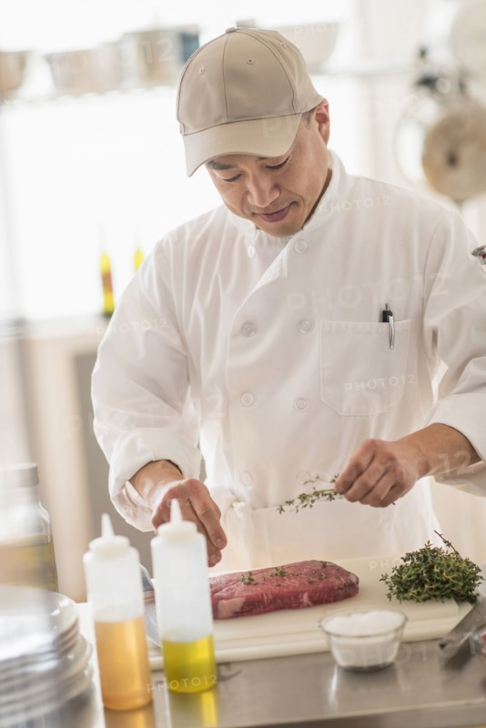 Korean chef seasoning meat in kitchen