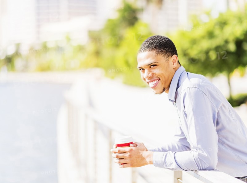 Black businessman leaning on banister at waterfront