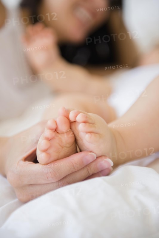 Close up of mixed race mother holding feet of baby
