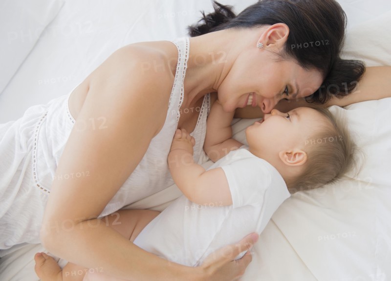 Overhead view of mixed race mother laying with baby on bed
