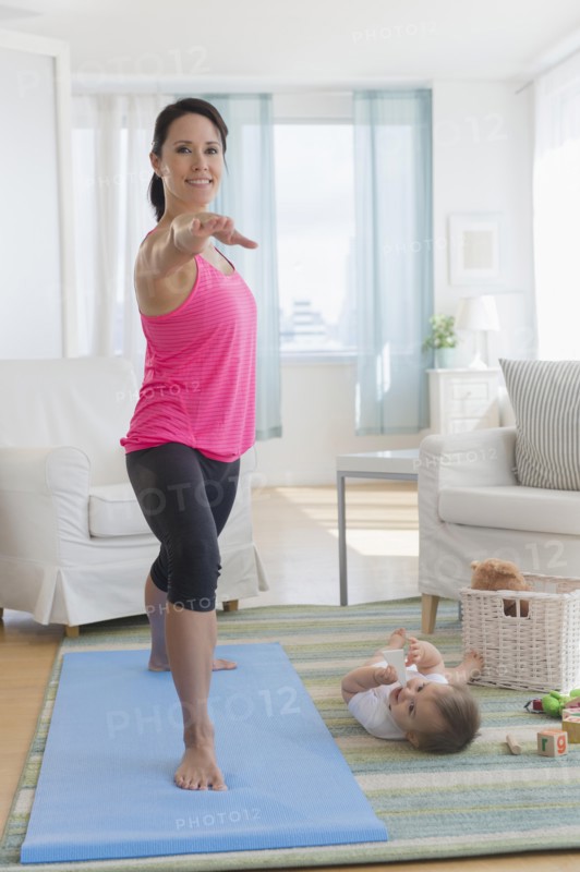 Mixed race mother practicing yoga and watching baby at home