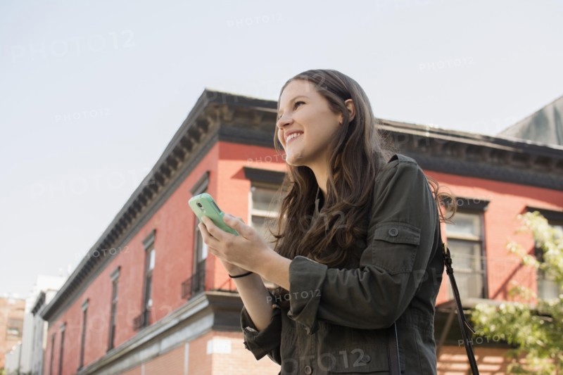Low angle view of Caucasian woman using cell phone outdoors