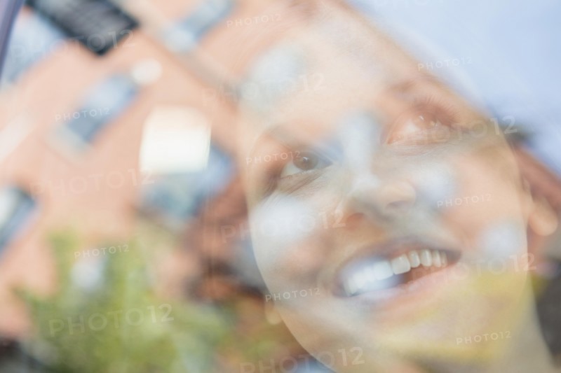 Caucasian woman and reflection of apartment buildings in window