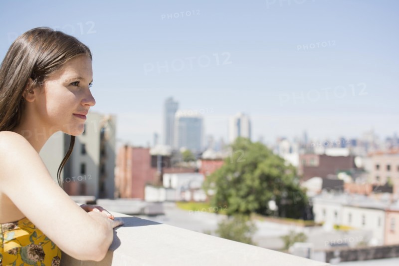 Caucasian woman overlooking cityscape from urban rooftop