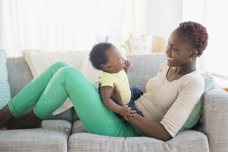 Black mother and son playing on sofa