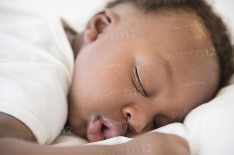 Close up of Black baby boy sleeping on bed