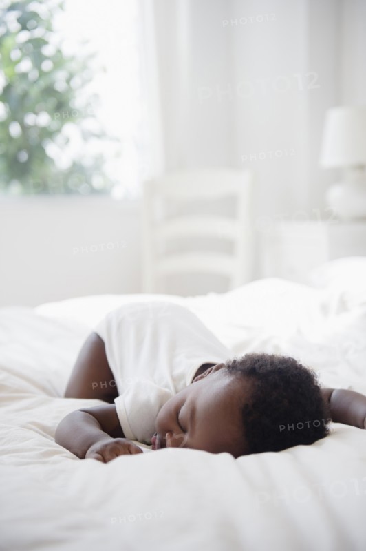 Black baby sleeping on bed