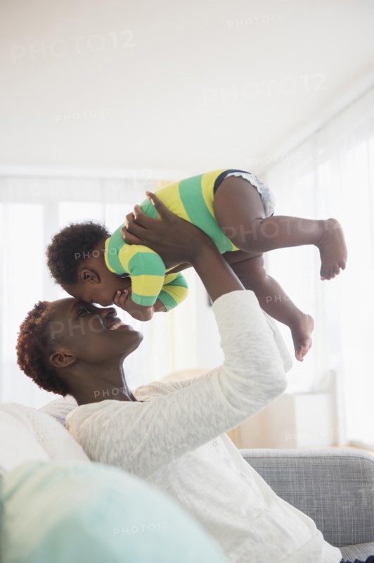Black mother playing with baby boy on sofa