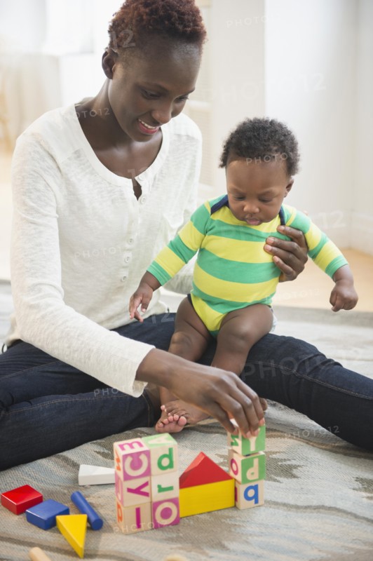 Black mother playing with baby boy in living room