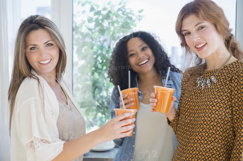 Women drinking healthy juice near window