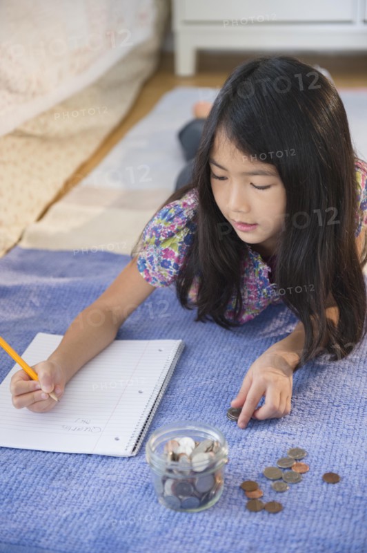 Vietnamese girl counting coins on bedroom floor