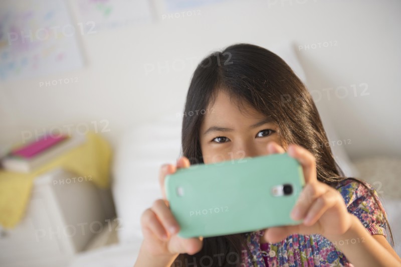 Smiling Vietnamese girl taking cell phone photograph