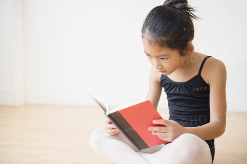 Vietnamese ballet dancer reading book in studio