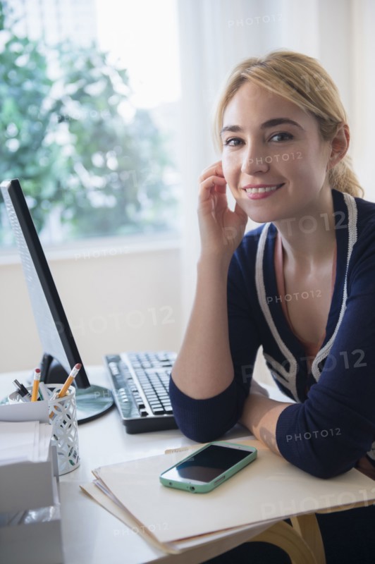 Caucasian businesswoman smiling at desk