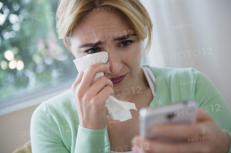 Crying Caucasian woman using cell phone