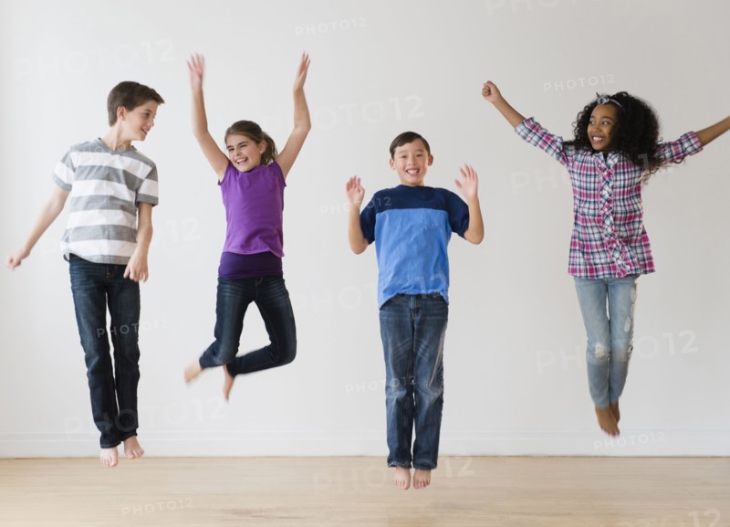 Smiling children jumping for joy in studio