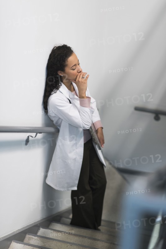 High angle view of stressed mixed race doctor standing on staircase
