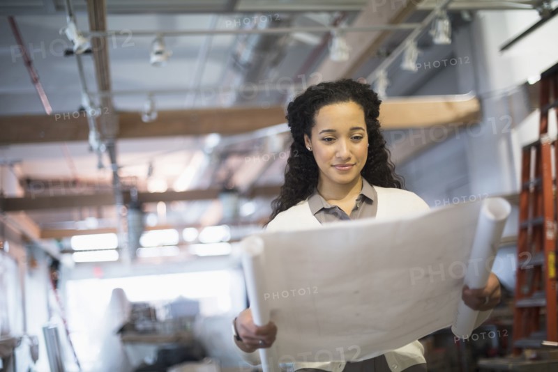 Mixed race architect reading blueprints