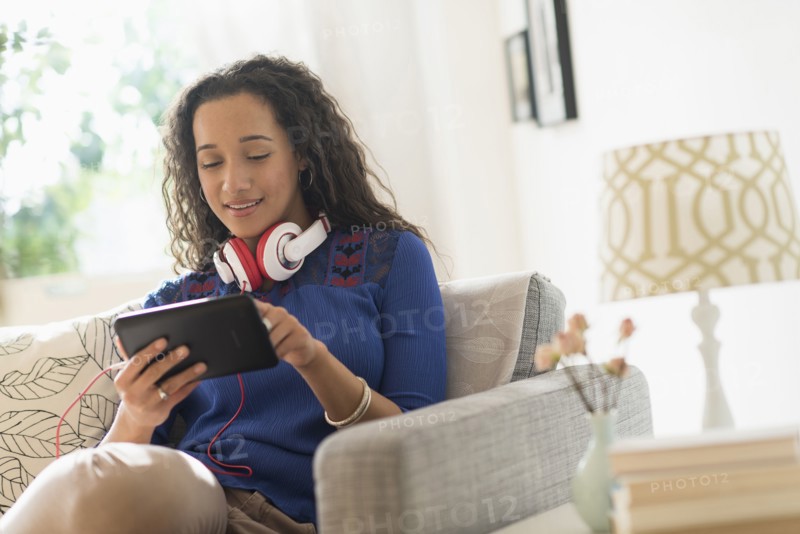 Mixed race woman using digital tablet on sofa