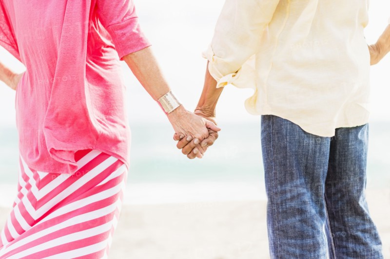Older couple holding hands on beach