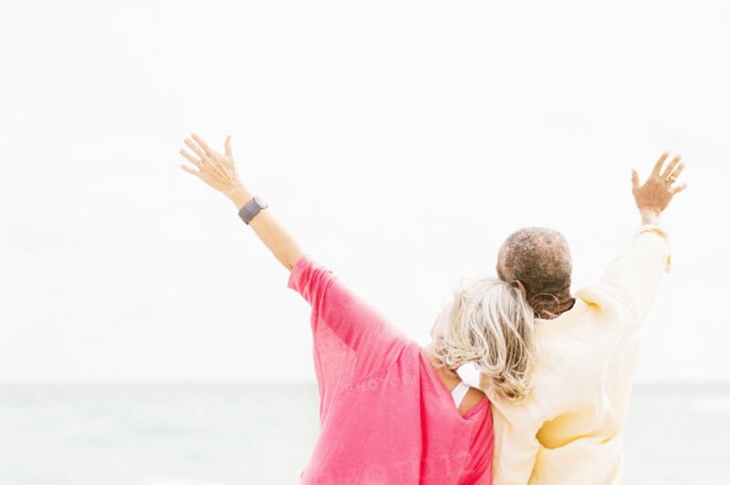 Older couple cheering and hugging on beach