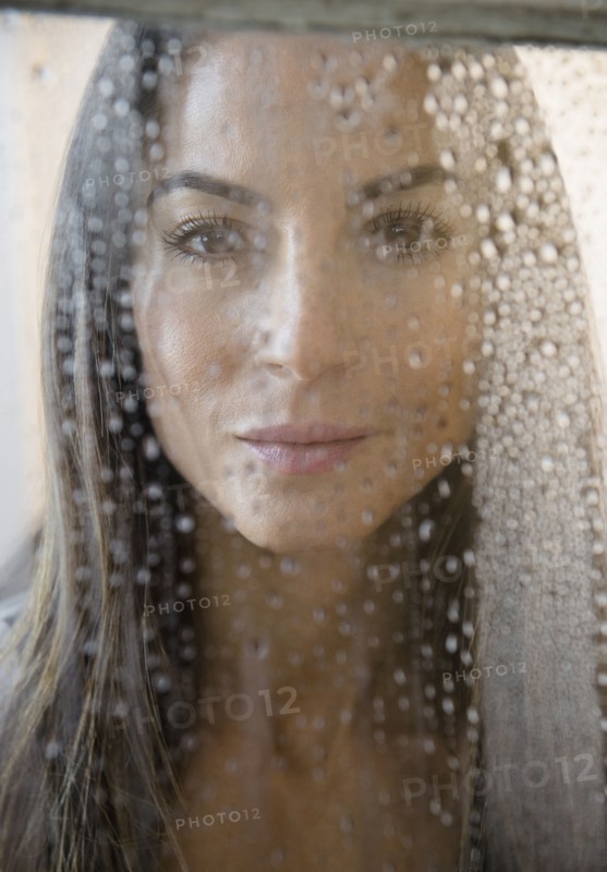 Caucasian woman peering through wet window