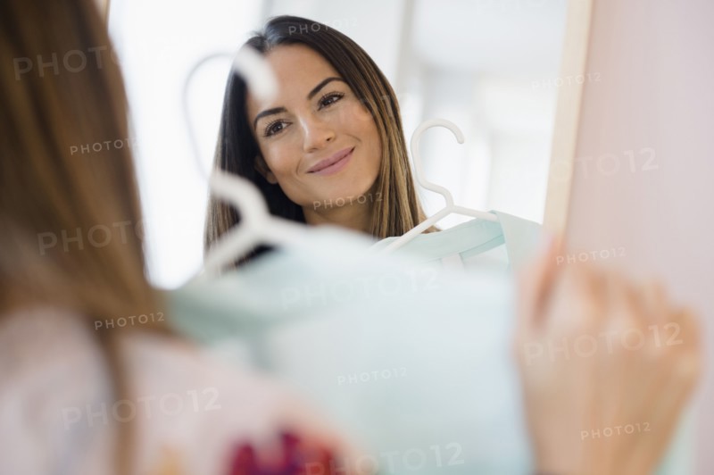 Caucasian woman admiring shirt in mirror