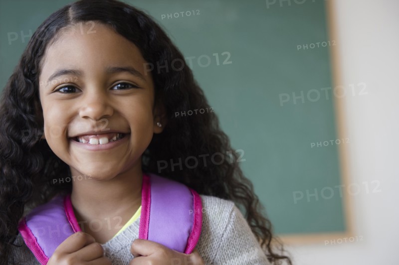 Smiling mixed race student wearing backpack in classroom