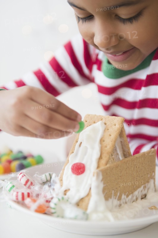 Mixed race girl decorating gingerbread house