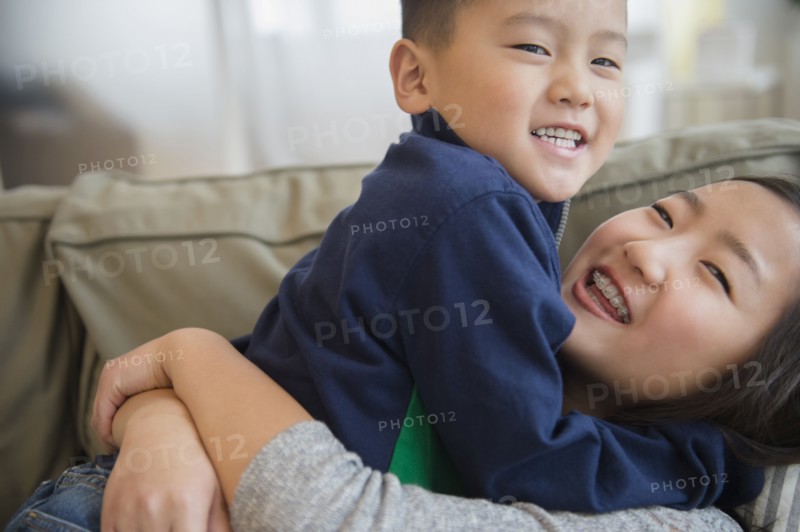 Asian brother and sister playing on sofa