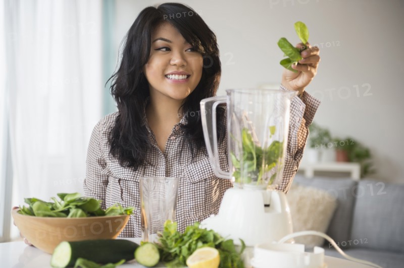 Pacific Islander woman making green smoothie in blender